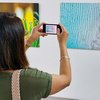 A woman taking a photo of a print on display